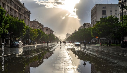 Portrait of a city view with puddles on the streets due to rain and reflection of sunlight in the puddles.