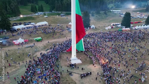 Drone View of Raising the largest and tallest Bulgarian flag on the highest pole on Rozhen Peak in the Rhodope Mountains, near Pamporovo resort, Bulgaria.