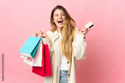 Young woman with shopping bag isolated on pink background holding shopping bags and a credit card
