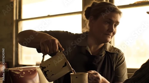 Woman pouring coffee in warm indoor lighting.