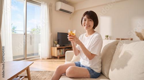 夏のリビングで麦茶を飲んで涼む女性