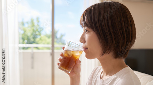 夏のリビングで麦茶を飲んで涼む女性