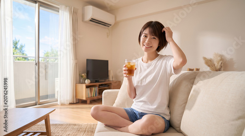 夏のリビングで麦茶を飲んで涼む女性