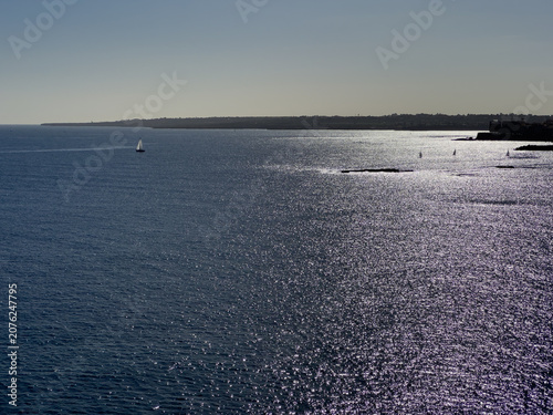 Aerial view of the sea and a sailboat in the background
