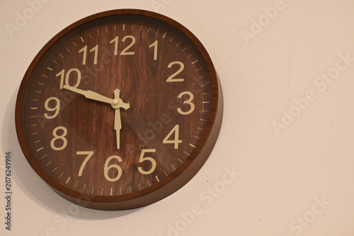 Wooden wall clock on plain wall