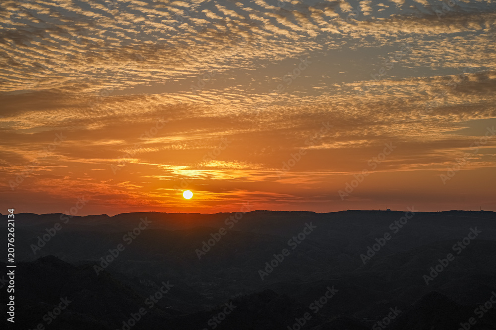 Fototapeta premium Golden sunset over mountain horizon with dramatic orange sky 