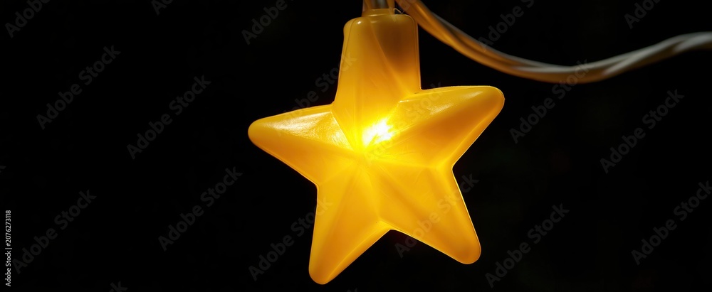 Fototapeta premium A softly illuminated yellow star ornament set against a dark festive backdrop, ideal for holiday themes.