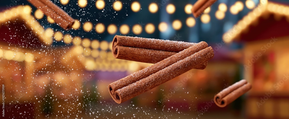 Fototapeta premium Floating cinnamon sticks surrounded by soft sugar sprinkles, set against a lively holiday market scene.