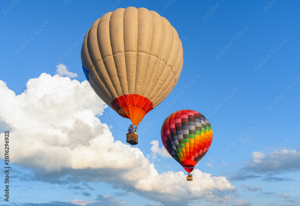 Naklejka premium Scenic flight of hot air balloons on a clear summer day among white clouds