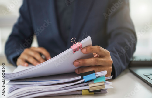 Business document organization with professional reviewing clipped paperwork and laptop to manage financial records audit compliance accounting workflow budget control and corporate productivity