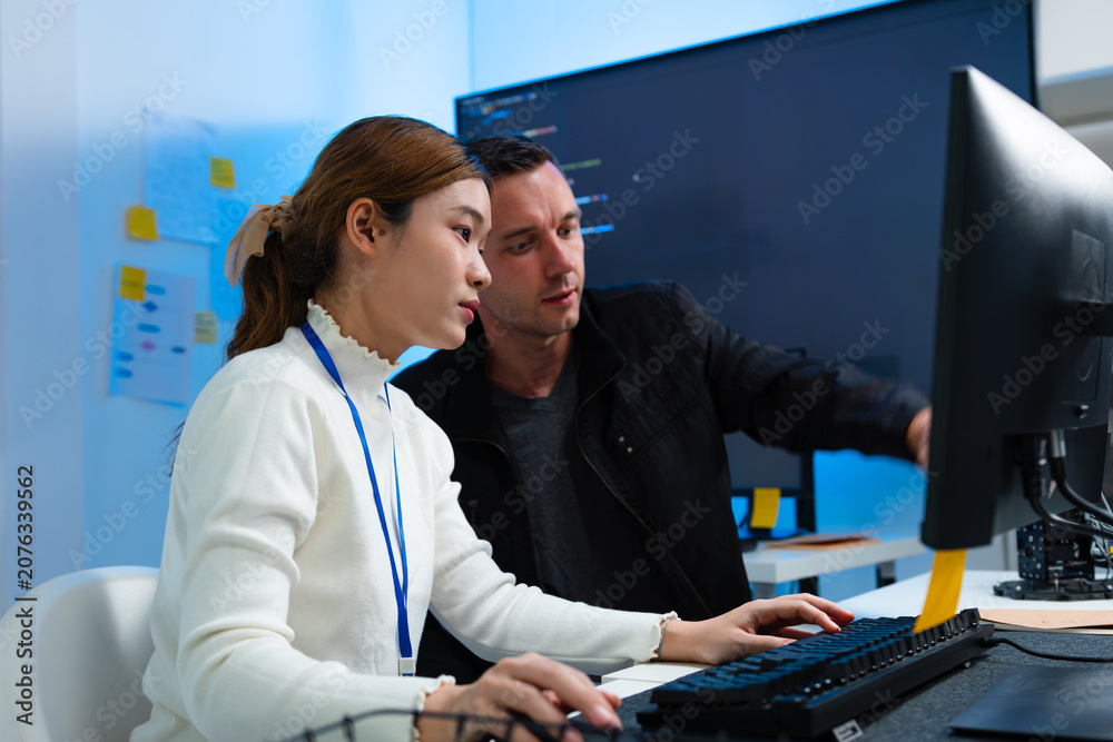 Fototapeta premium Two software Engineer Collaboration on Software Development Project, working together on Computer, Programmer Discussion, Reviewing Code on Screen Analyzing, Developing Idea at Desk in tech Office.