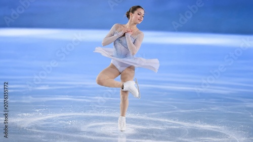 Professional Female Figure Skater Performing Elegant Spin on Indoor Ice Rink Arena