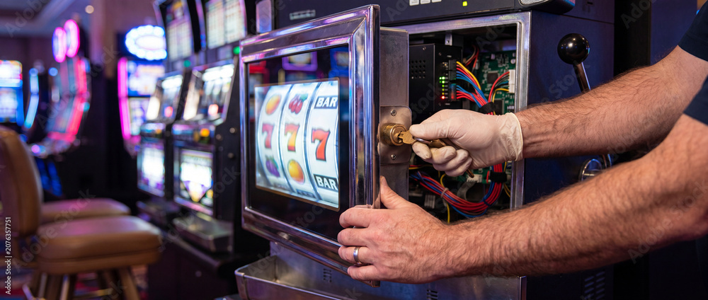 Naklejka premium Technician opening electronic slot machine panel on bright casino