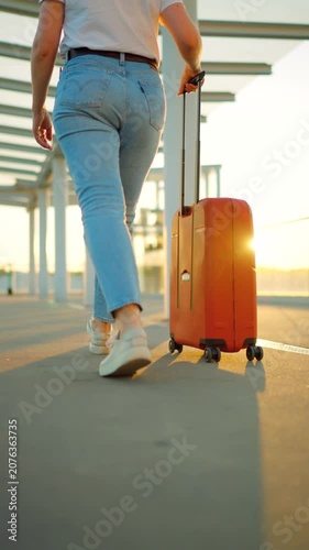 Woman confidently pulling a suitcase in an airport terminal. Back view