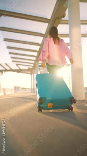 Woman confidently pulling a suitcase in an airport terminal. Back view