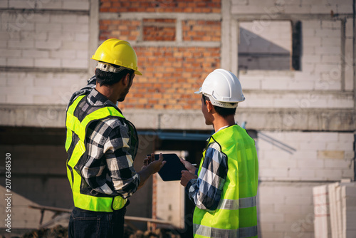 Asian Adult Construction Workers Discussing Plans on a Tablet at