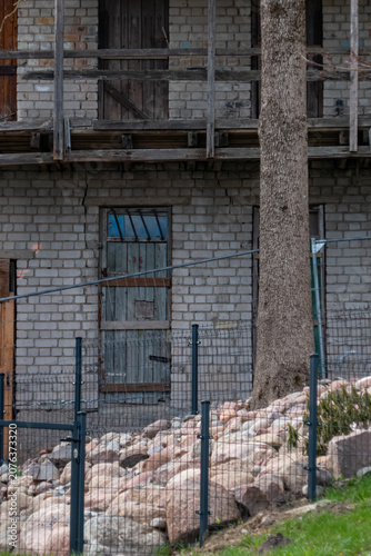 Old brick building with wooden balcony and fenced yard