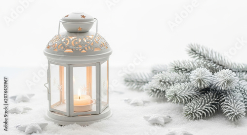White winter lantern with burning candle and frosted spruce branches on snowy background providing cozy holiday atmosphere and festive decor.