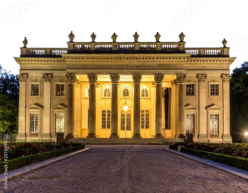 Historic neoclassical building with yellow columns at dusk.