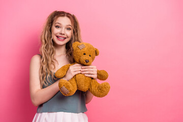 Young girl with a teddy bear posing in a pink studio background smiling for cheerful lifestyle stock photo