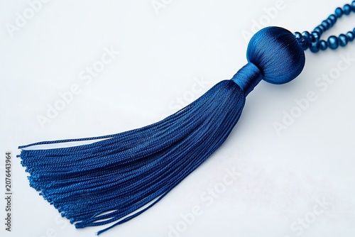 Blue silk tassel with decorative bead and matching string isolated on white background