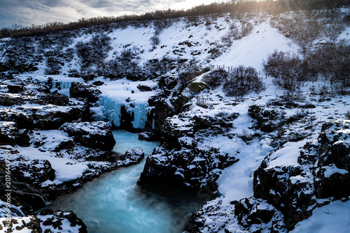 Beautiful winter view of Barnafoss waterfall with turquoise blue water and frozen ice formations, Iceland