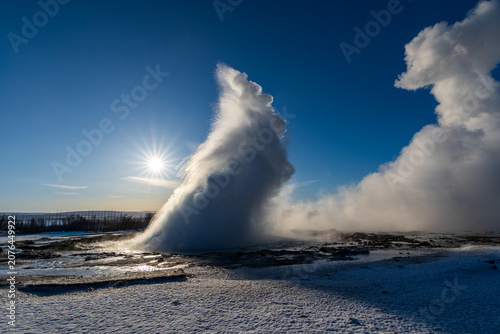 Quadro su tela Strokkur geyser eruption with water splash and steam under a bright winter sun,