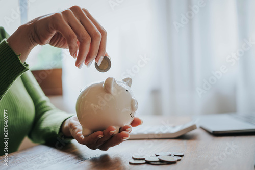 Woman Putting Coin into Piggy Bank for Personal Savings