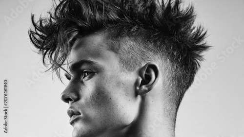 Stylish young male model with futuristic textured hawk hairstyle profile view
