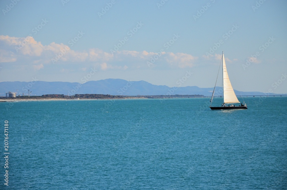 Obraz premium serene marine scene with a sailboat sailing in coastal waters
