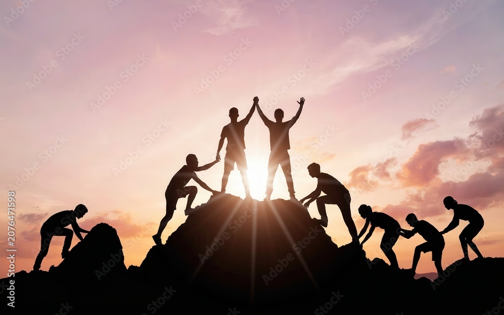 Fototapeta premium Silhouettes of team climbing a mountain at sunset