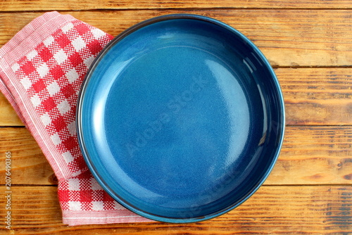 There is an empty ceramic plate on a wooden background.