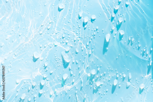 Blue water with ripples on the surface. Defocus blurred transparent blue colored clear calm water surface texture with splashes and bubbles. Water waves with shining pattern texture background.