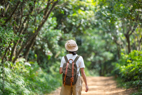 Hiker with backpack walking through lush forest