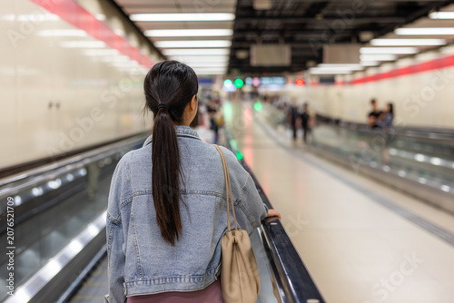 Young woman standing on station escalator
