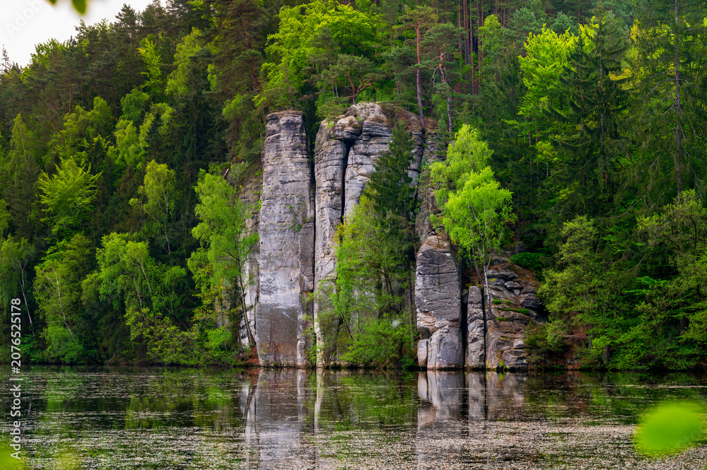 Fototapeta premium Iconic sandstone cliffs reflected in the calm waters of Vezicky Pond (Vezicky rybnik in czech) in the beautiful Bohemian Paradise, Czech Republic, a famous scenic destination popular with tourists.