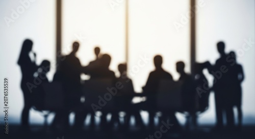 Silhouettes of people gathered around a conference table in discussion