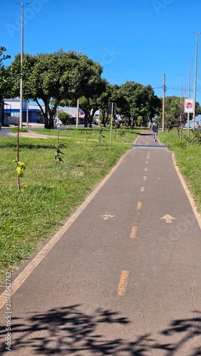 Straight outdoor bike lane with directional arrows surrounded by nature under a clear sky