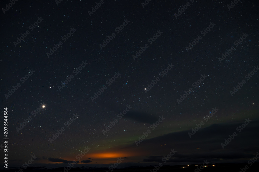 Fototapeta premium Green northern lights dancing over snowy mountains in Iceland night sky