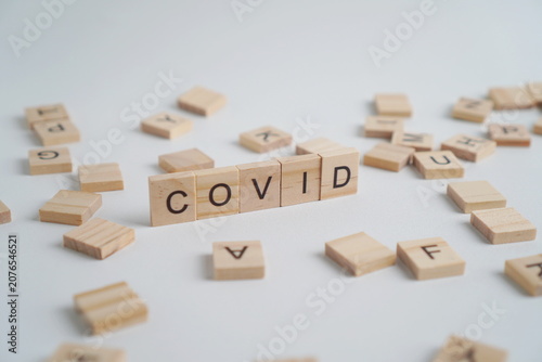 Tableau sur toile The word COVID on a wooden block isolated on a white background with several wooden letter blocks as its border