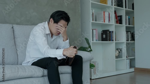 Depressed young Asian man addicted feeling bad drinking whiskey alone at home, stressed frustrated lonely drinking alcohol suffers from problematic liquor, alcoholism, life and family problems