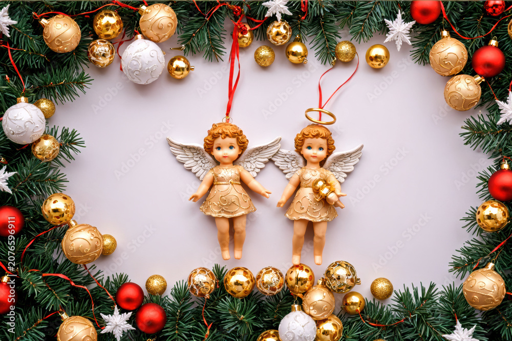 Obraz premium Two Christmas angels surrounded by festive gold and red ornaments on pine branches