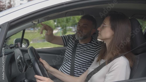 Instructor guiding woman to drive a car