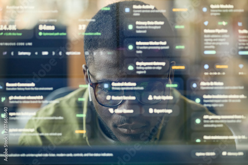 Close up of young Black man analyzing software dashboard on computer, monitoring data and coding workflow. Ideal for cybersecurity, analytics, fintech, remote tech work