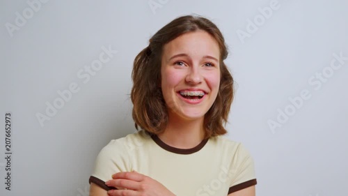 authentic and joyful laughter of a young woman with braces, eyes closed in pure happiness, celebrating positive emotions and genuine amusement