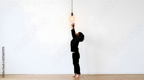 Person reaching up to touch light bulb hanging from ceiling in empty room