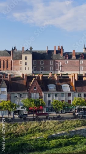 Daytime footage of the Chateau de Gien and traditional French houses along the Loire riverbank in Gien, Centre-Val de Loire, France. The video shows the iconic red brick chateau with its towers and