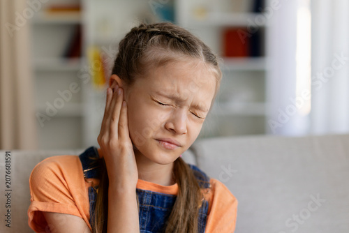 Foto Teen girl holding her ear with eyes closed, showing discomfort from earache, ups