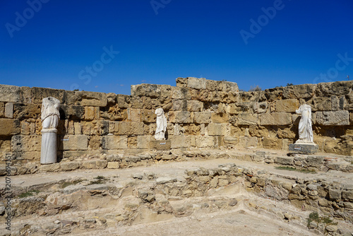 Ruins of the ancient city of Salamis, North Cyprus. The image shows marble statues, typical of Greco-Roman architecture. The statues, lacking heads, are draped in classical attire.