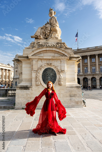 Foto Elegant fashion influencer Greta Gardner (Ivana Benko) wearing a luxurious long red tulle dress at Place de la Concorde in Paris, posing in front of a majestic historical monument under a blue sky